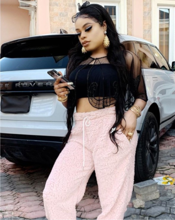 Bobrisky posing beside his Range Rover